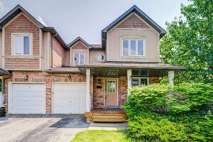 Front elevation of a detached brick home with double garage and landscaped front yard.