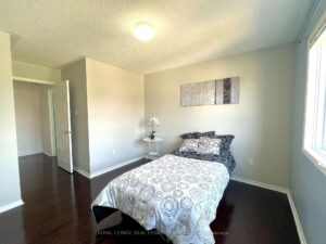 Secondary bedroom with hardwood flooring, large window, and neutral décor.