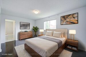 Spacious bedroom with hardwood flooring, dresser, and large window.