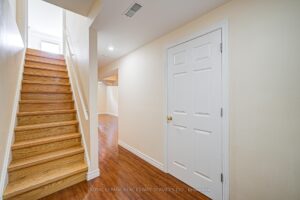 Staircase with hardwood flooring and storage closet.