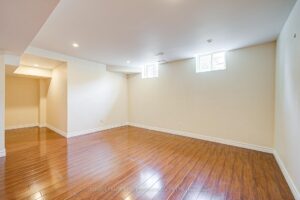 Finished basement recreation room with hardwood flooring and recessed lighting.