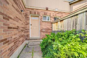 Side entrance with brick exterior, private gate, and fenced walkway.