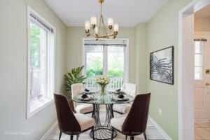 Bright dining area with large window, modern chandelier, and hardwood flooring.