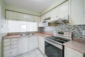Modern kitchen with white cabinetry, tile backsplash, and stainless steel appliances.