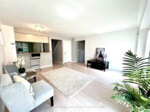 Open-concept living room with large window and adjoining kitchen.