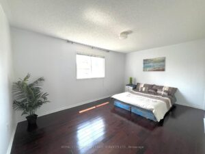 Bright primary bedroom with hardwood flooring and large window.