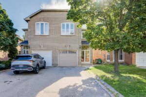 Two-storey detached home with brick exterior, attached garage, and mature front landscaping.