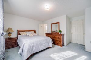 Spacious primary bedroom with large window, plush carpeting, and neutral décor.