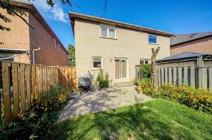 Rear exterior of the home featuring a private fenced backyard and landscaped gardens.