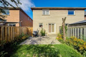 Backyard view of the two-storey home with stone patio and green lawn.