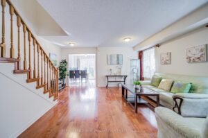 Bright living room with hardwood flooring, staircase, and open layout to the dining area.