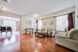 Spacious living room with large front window, hardwood floors, and abundant natural light.