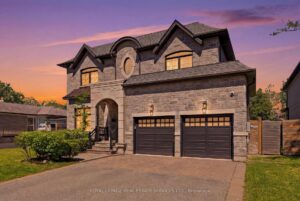 Twilight front exterior of a luxury two-storey home with stone façade, landscaped yard, and double garage.