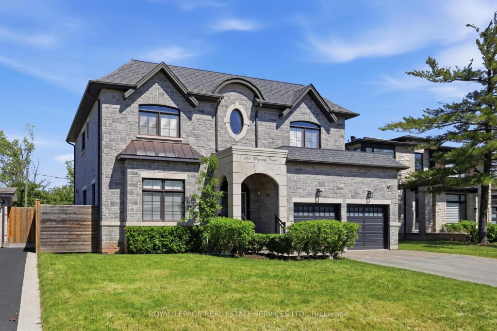Front elevation of the detached home featuring a stone and stucco exterior, double garage, and manicured landscaping.