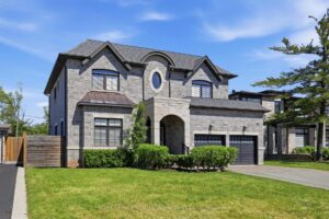 Front elevation of the detached home featuring a stone and stucco exterior, double garage, and manicured landscaping.