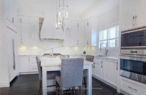Bright formal dining room with elegant chandelier, hardwood flooring, and contemporary décor.